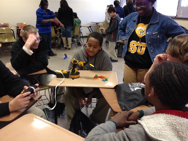 Camp IT Attendees attempt to maneuver a robot to pick up blocks after watching a demonstration performed during a robotics mini-camp in February.
